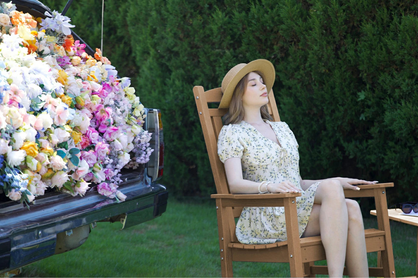 Woman sitting in a chair next to a truck filled with flowers in an outdoor setting