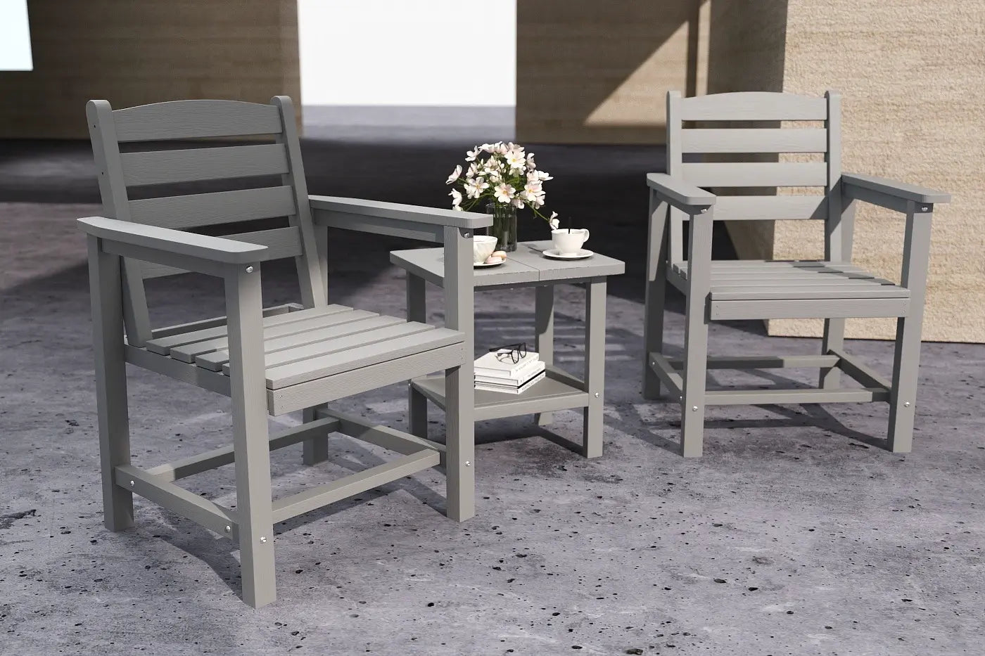 Two gray chairs and a small table with a flower arrangement on a concrete surface.