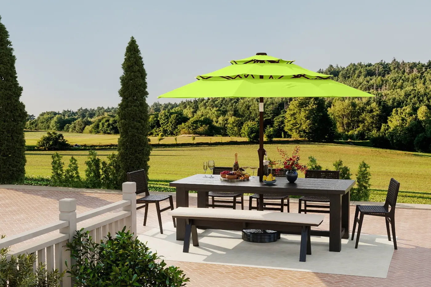 Outdoor patio set with a large green umbrella, table, chairs, and a fire pit on a deck with a scenic background.