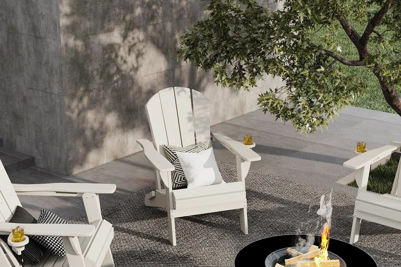 White Adirondack chairs around a fire pit with a tree and concrete wall in the background
