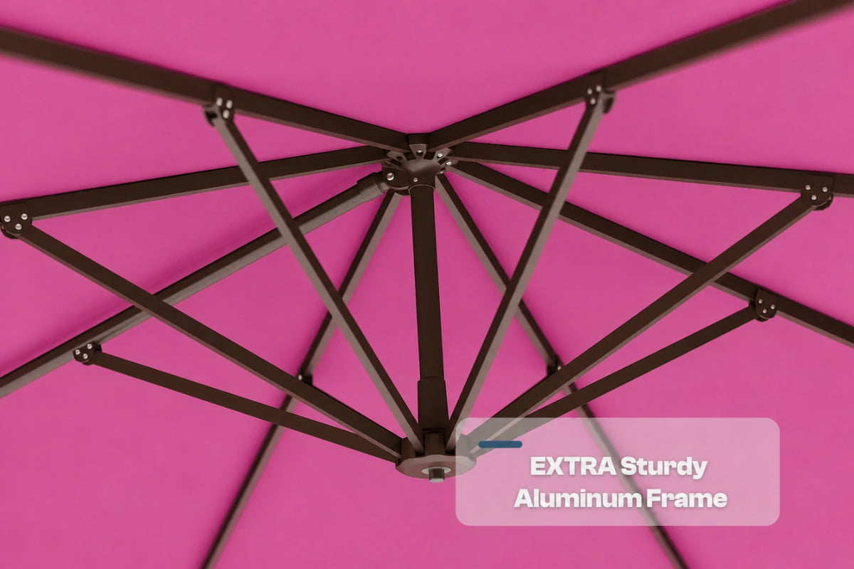 Close-up underside view of a rose pink patio umbrella showing the dark aluminum canopy frame structure, with a text overlay that reads 'EXTRA Sturdy Aluminum Frame'.