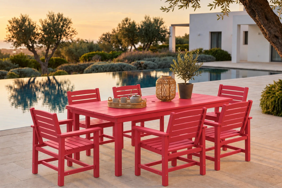 A red outdoor dining set consisting of a rectangular table and six matching slatted chairs, arranged on a patio beside an infinity pool at sunset. Decorative items on the table include a woven lantern and a small potted plant.