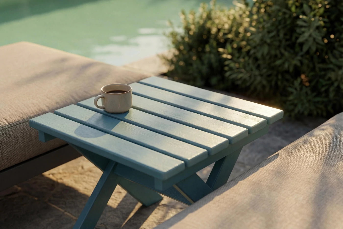 Blue outdoor table with a cup on it by a poolside