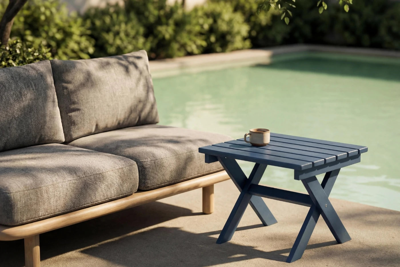 Outdoor setting with a gray sofa and small blue table by a pool