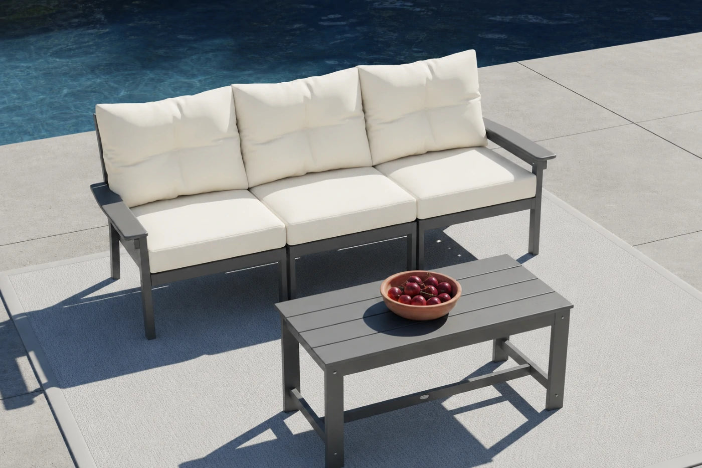 Outdoor patio set with a sofa and coffee table by a pool
