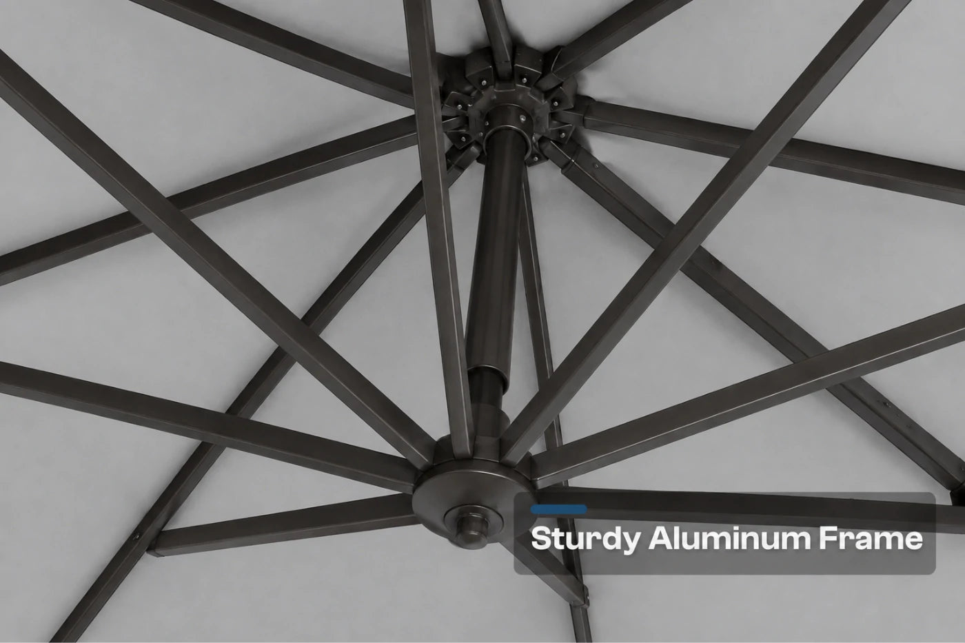 Close-up of a black aluminum patio umbrella frame with radiating ribs against a gray canopy background, with a text overlay reading 'Sturdy Aluminum Frame'.