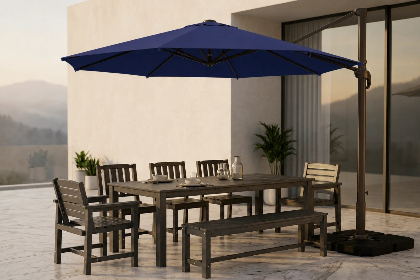 Outdoor patio dining set with a rectangular table, matching chairs and bench, and a large navy blue cantilever umbrella on a tiled terrace beside a modern building.