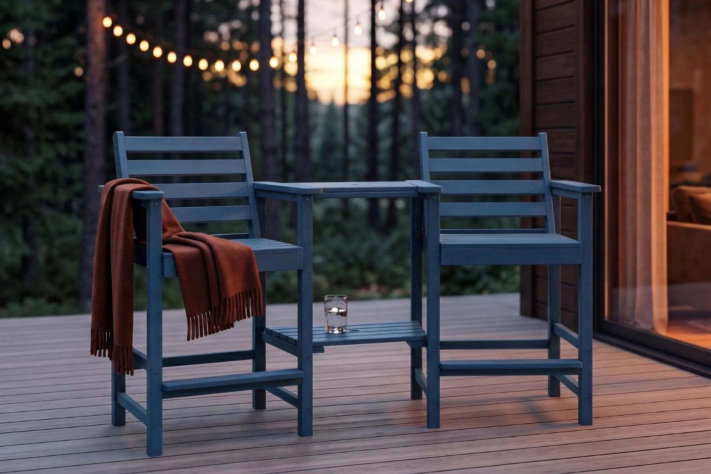 Two blue chairs with a small table on a wooden deck during sunset.