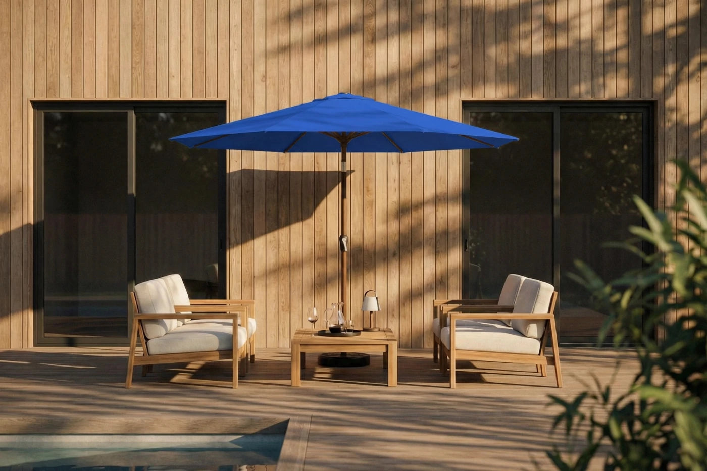 Outdoor patio set with two chairs and a table under a blue umbrella against a wooden wall.