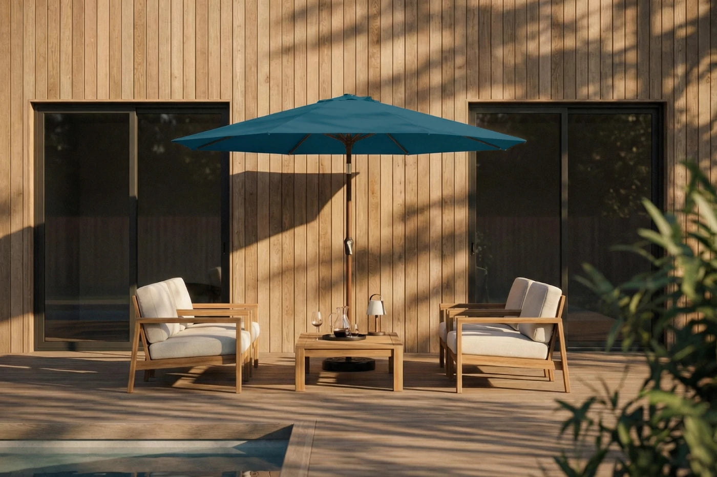 Outdoor patio set with two chairs and a table under a blue umbrella against a wooden wall.