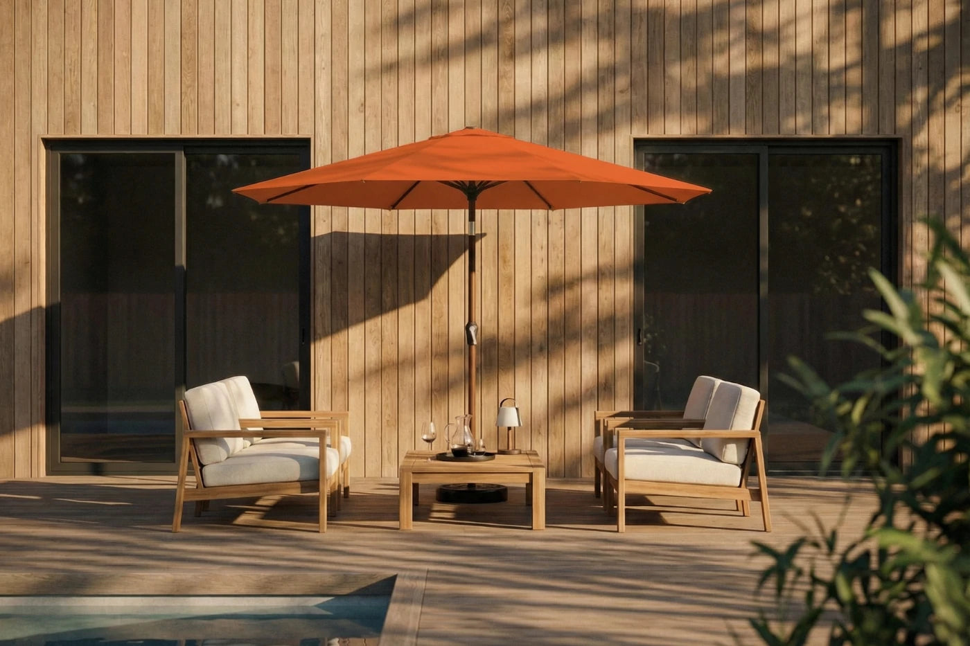 Outdoor patio set with two chairs, a table, and an orange umbrella against a wooden wall.
