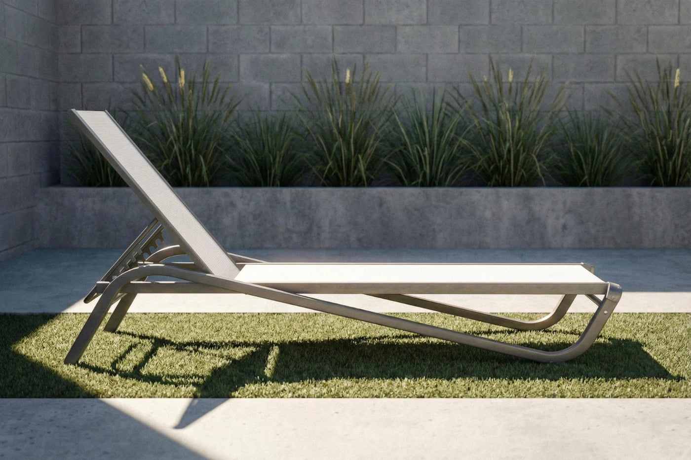 Modern outdoor lounge chair on grass with a stone wall and plants in the background