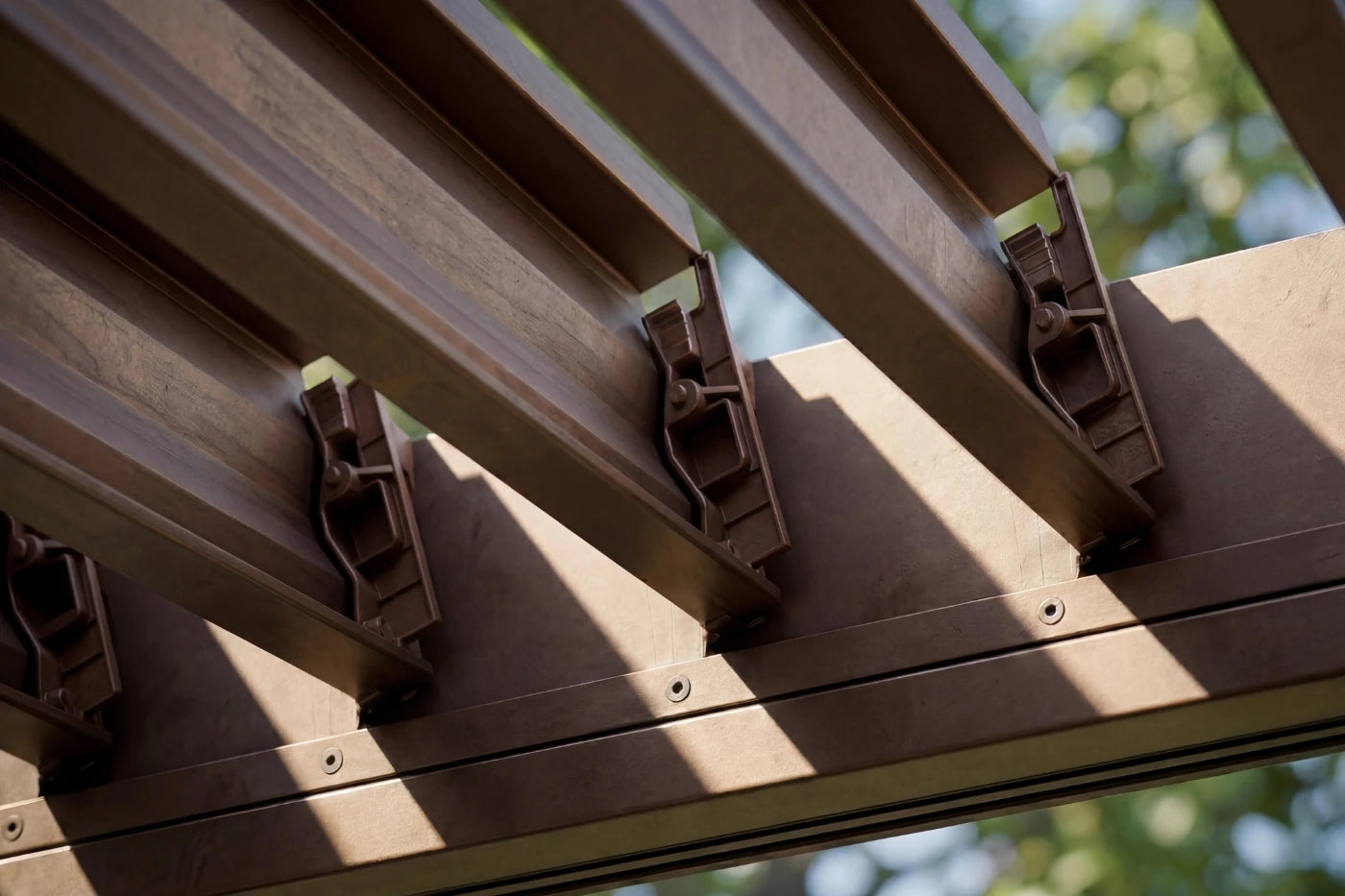 Close-up of a metal roof structure with visible fasteners against a blurred natural background