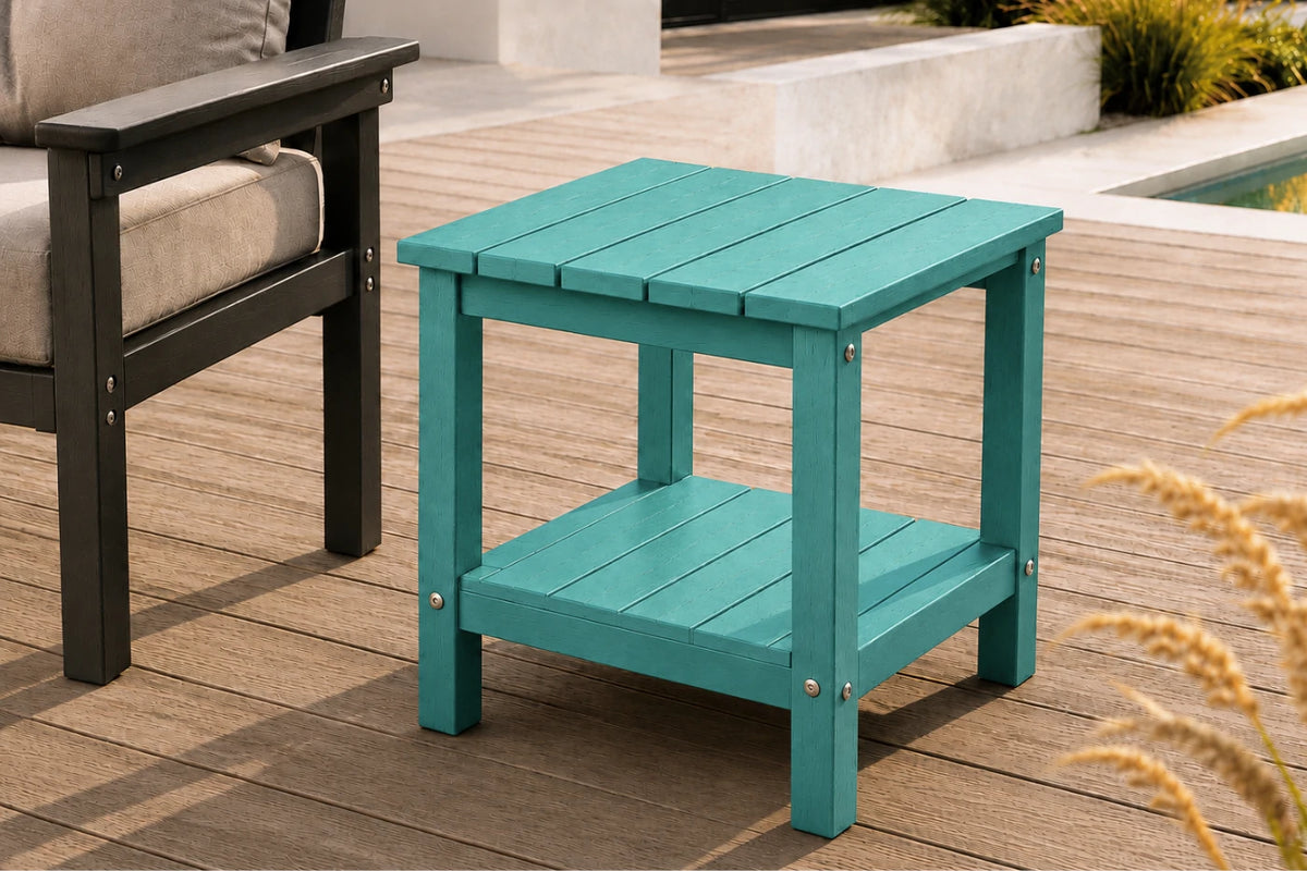 A teal outdoor end table with a slatted top and lower shelf, shown on a wooden deck next to patio furniture.