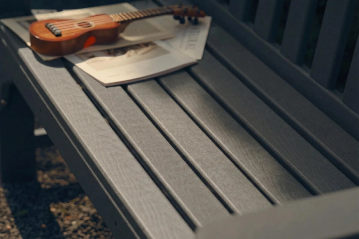 Small wooden guitar on a gray bench with a blurred background