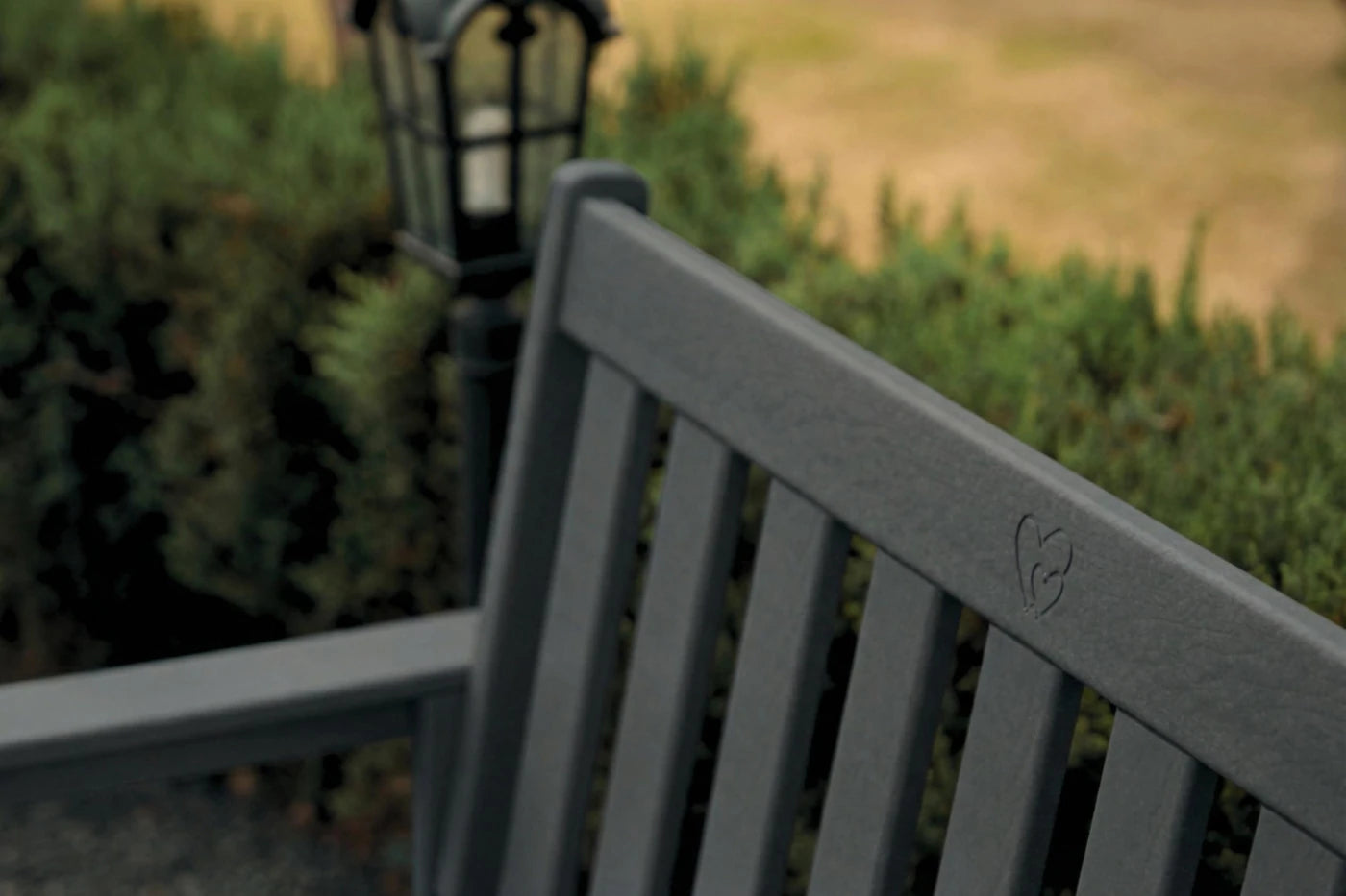 Gray bench with a blurred background of greenery and a lamp post