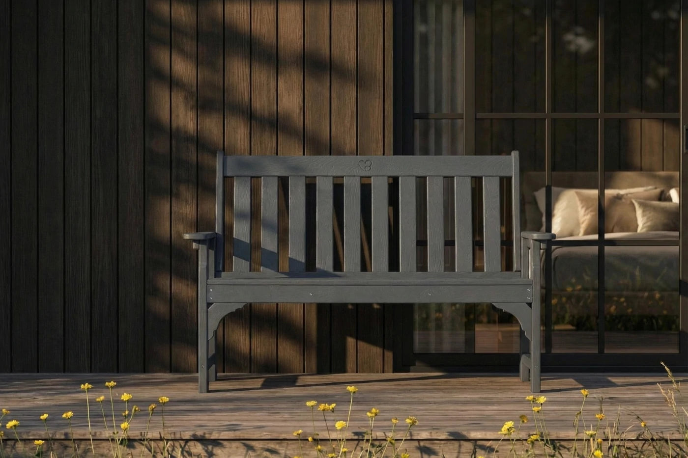 Wooden bench on a wooden deck with a dark wooden wall and window in the background.
