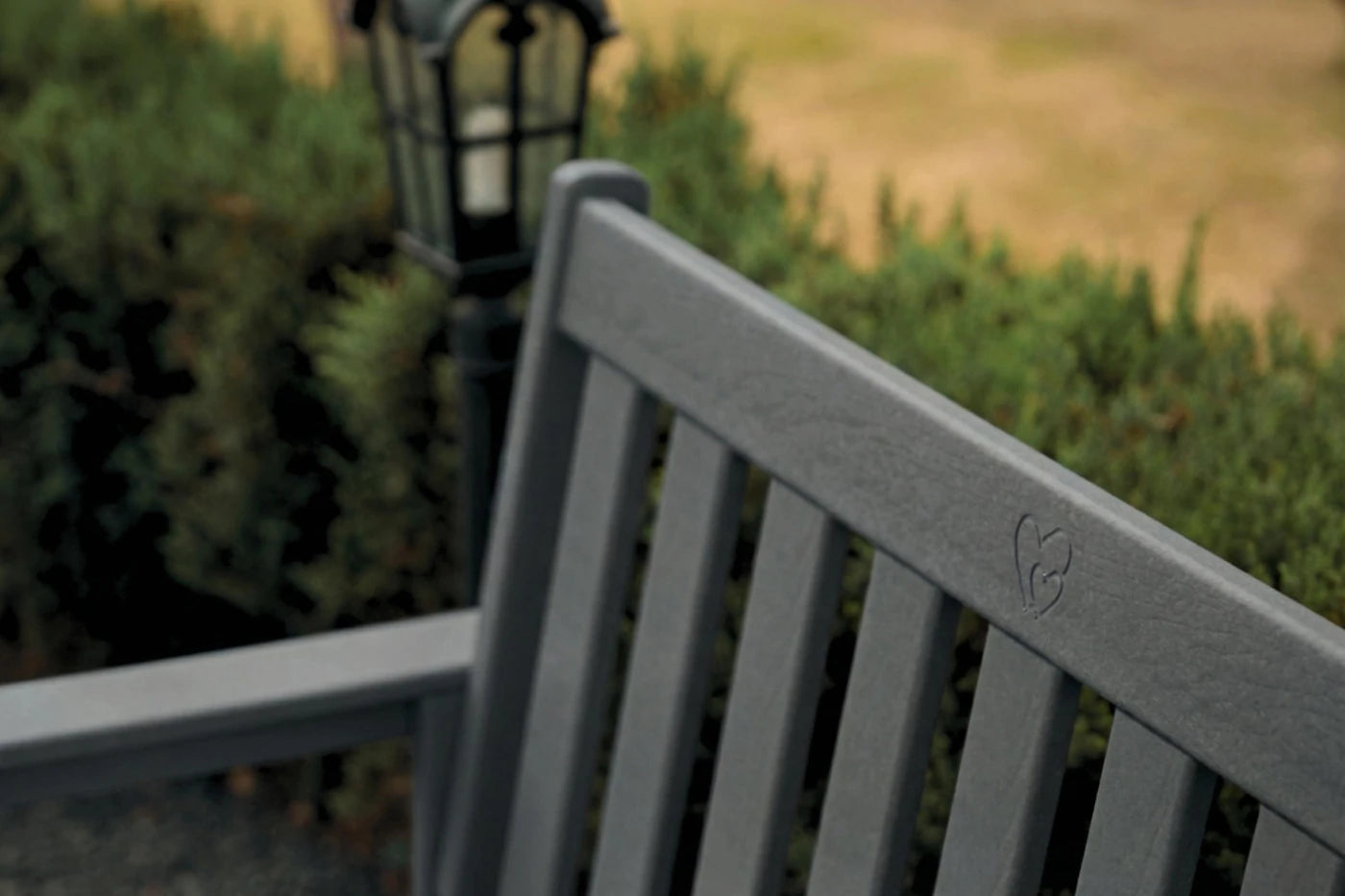 Gray bench with a blurred background of greenery and a lamp post