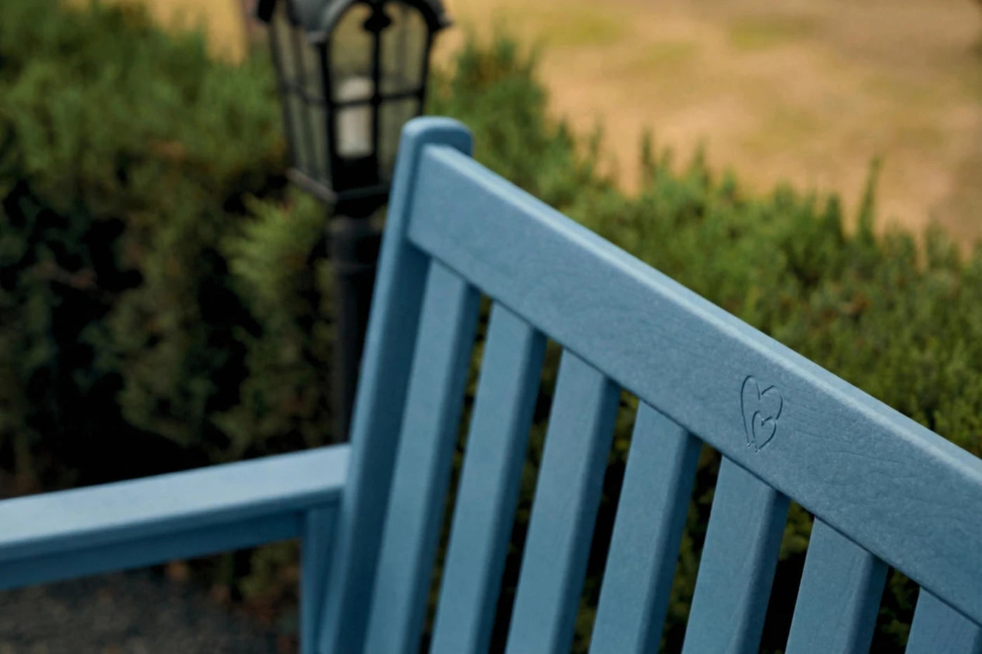 Blue bench with a blurred background of greenery and a lamp post.