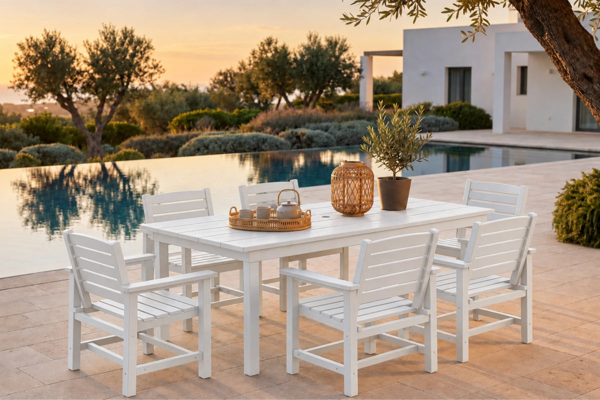 White outdoor dining set with a rectangular slatted table and six matching armchairs, styled on a patio beside a swimming pool at sunset.
