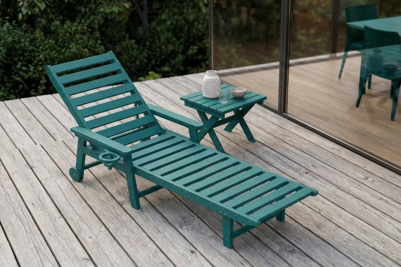 Green lounge chair and small table on a wooden deck with a blurred background
