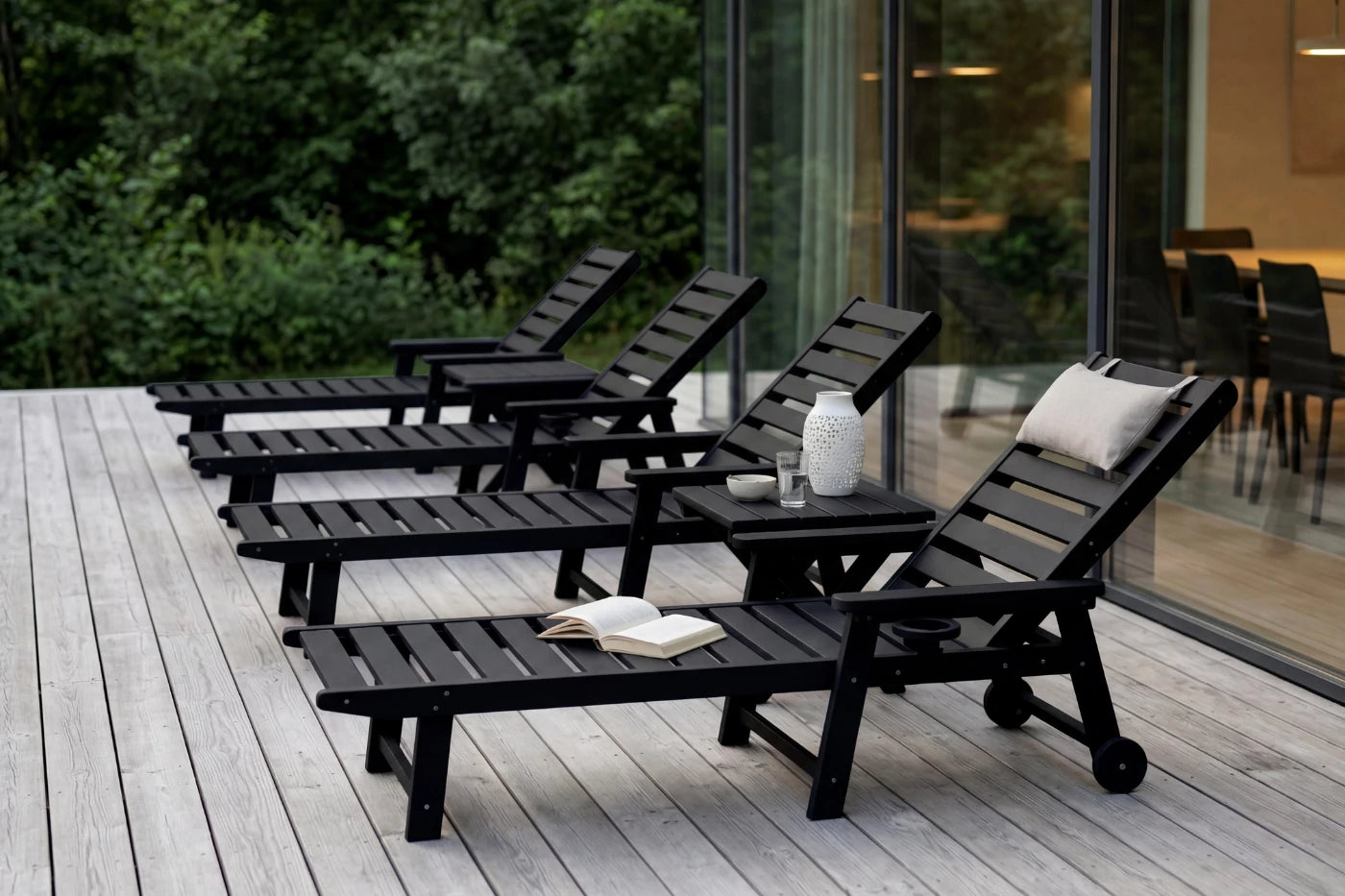 Black outdoor lounge chairs on a wooden deck with a modern building in the background