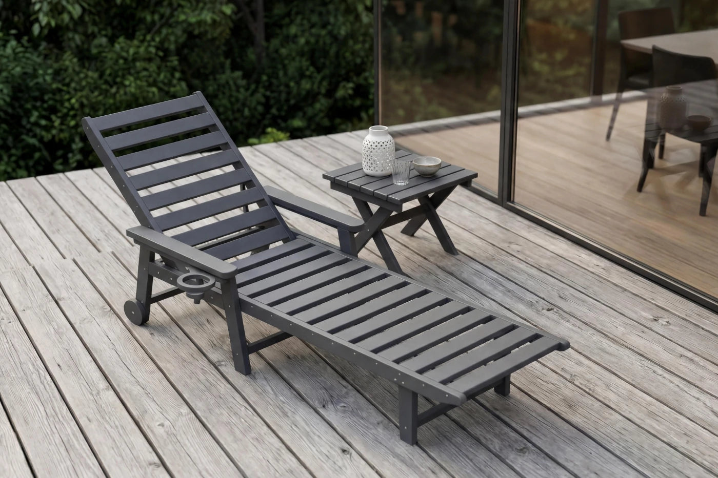 Gray lounge chair and small table on a wooden deck with a blurred background