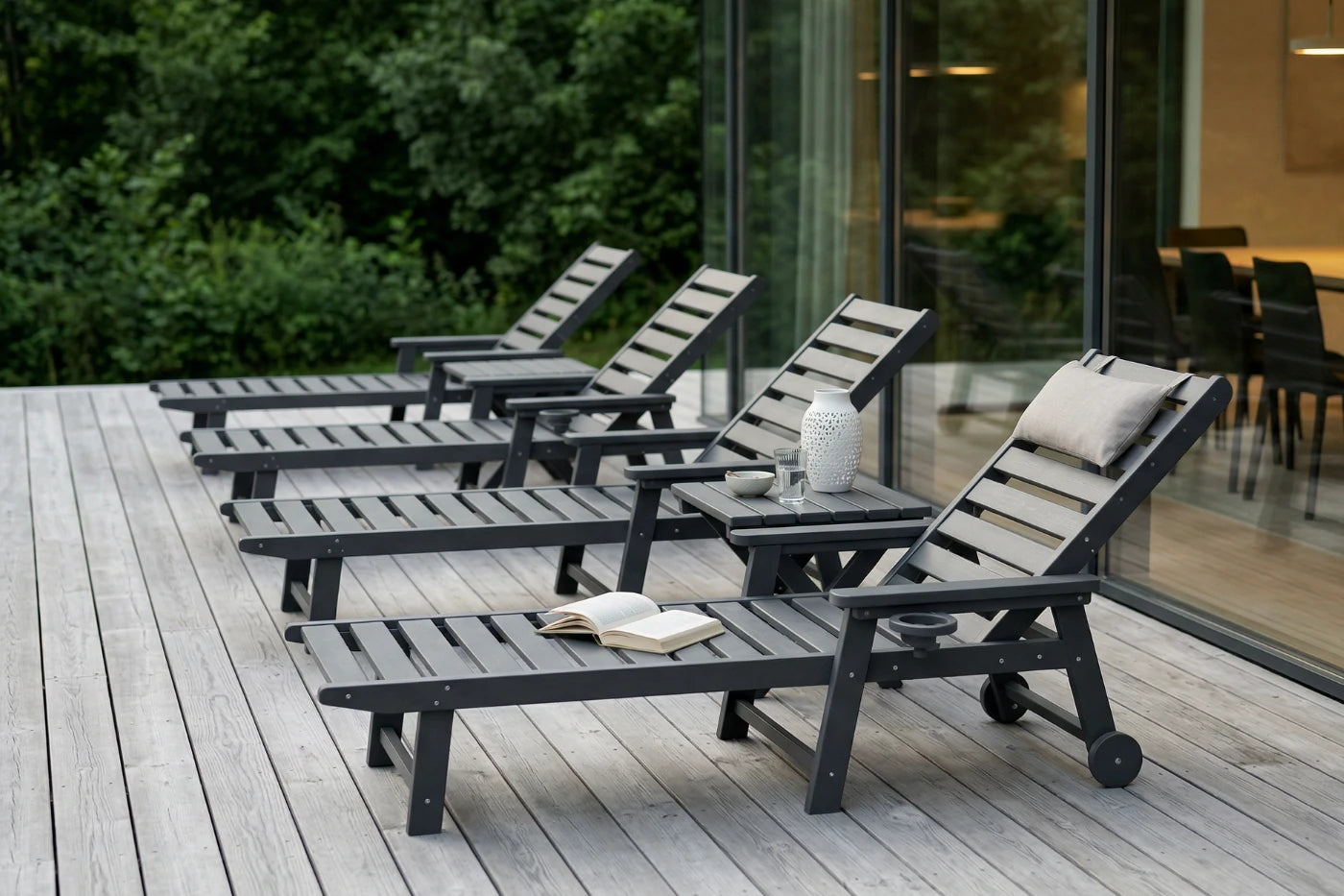 Set of outdoor lounge chairs on a wooden deck with a modern building in the background.