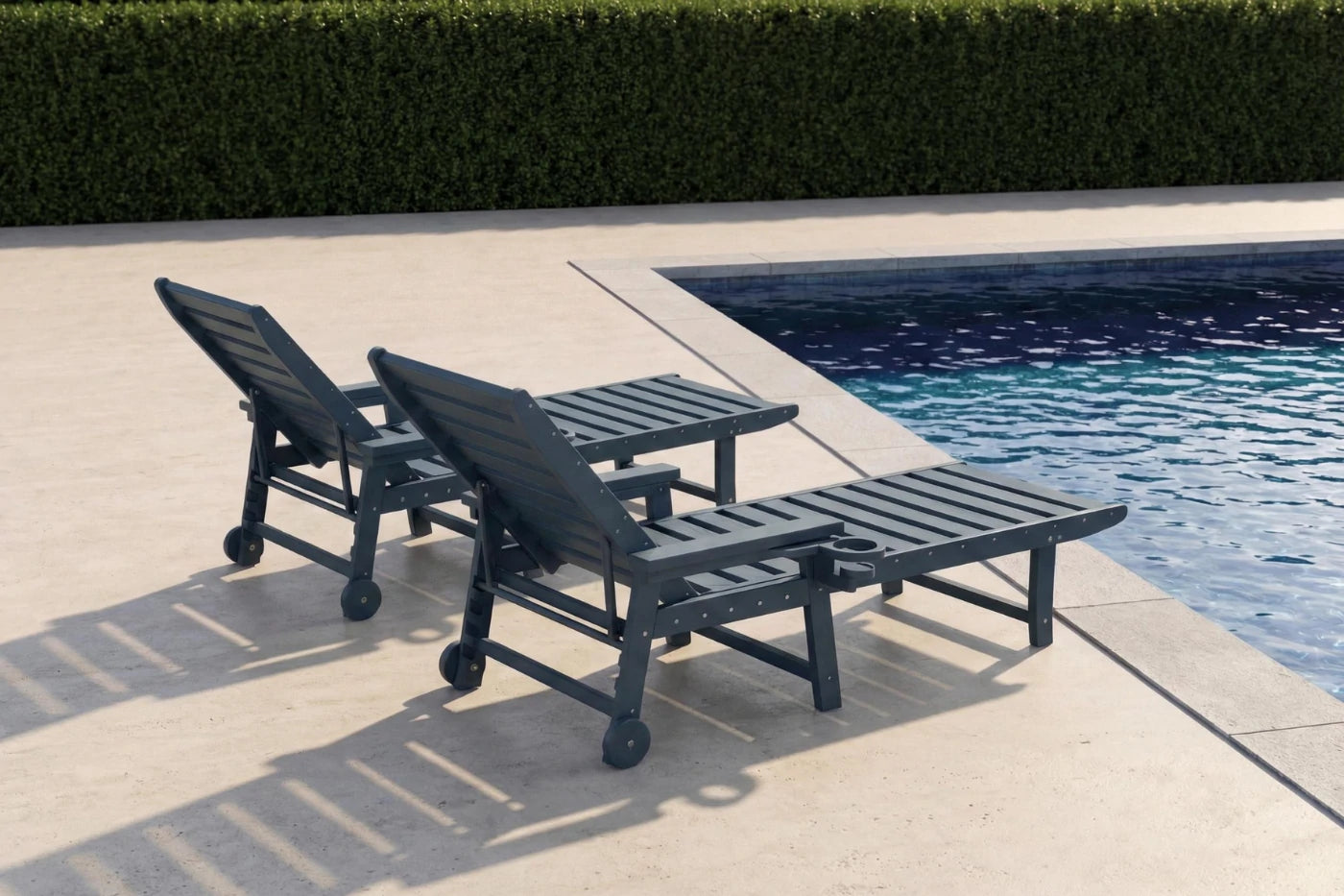 Two black lounge chairs by a pool with greenery in the background