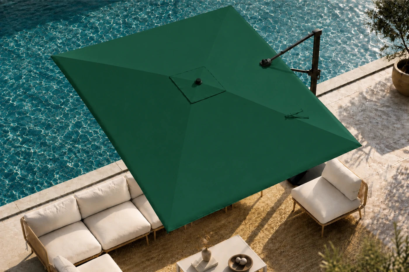 A large green patio umbrella with a cantilever arm is positioned over a modern outdoor lounge area next to a swimming pool.