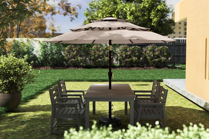 Garden setting with a patio table and chairs under a large umbrella on a sunny day.