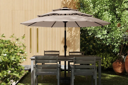 Outdoor patio set with table and chairs under a large umbrella in a garden setting.