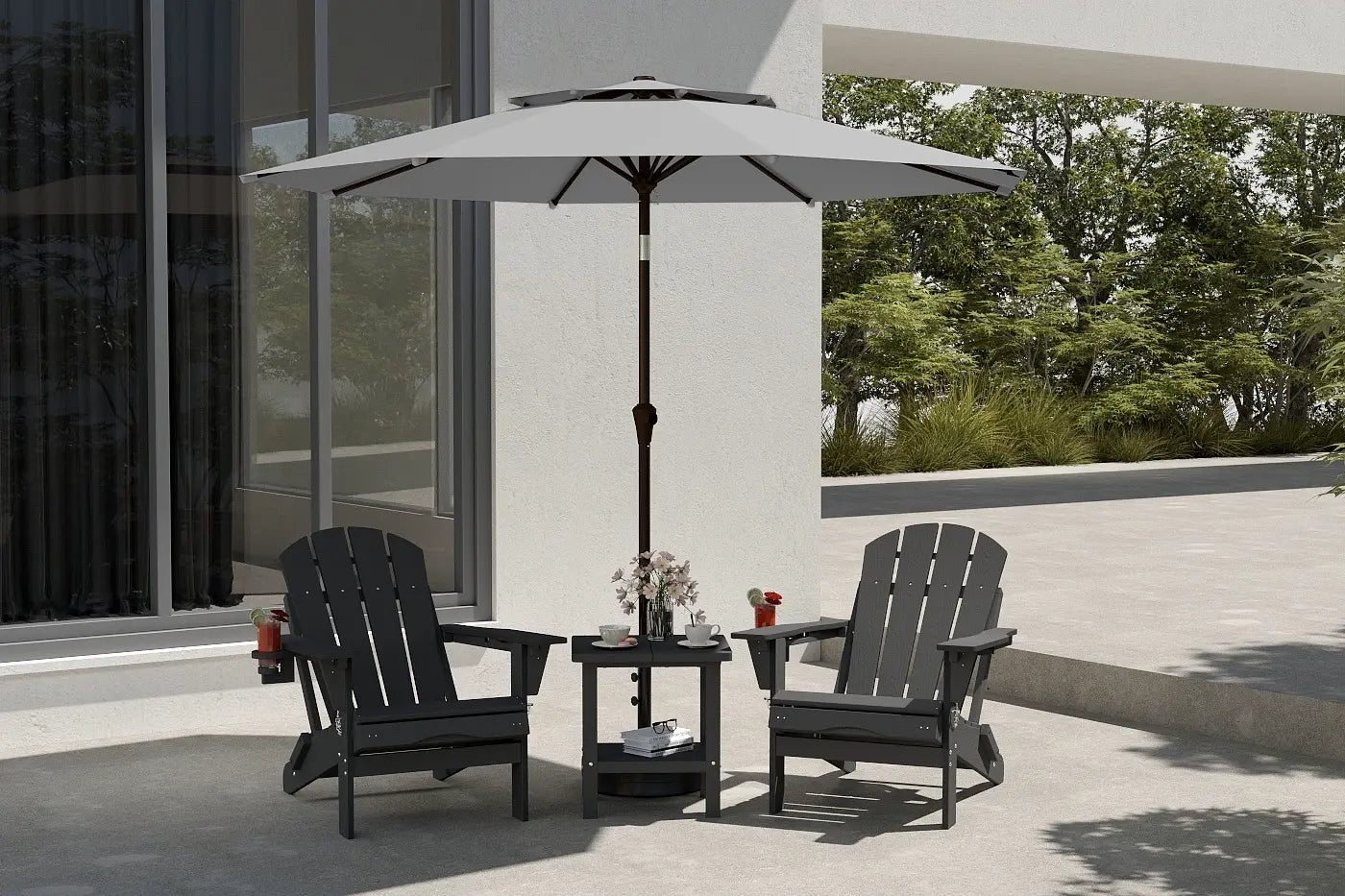Two black Adirondack chairs with a small round table and umbrella on a patio.