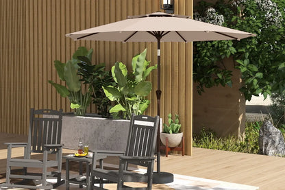 Patio set with chairs, table, and umbrella on a wooden deck with plants in the background.