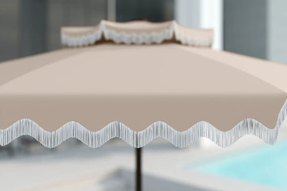 Beige outdoor umbrella with wavy edge design on a blurred background