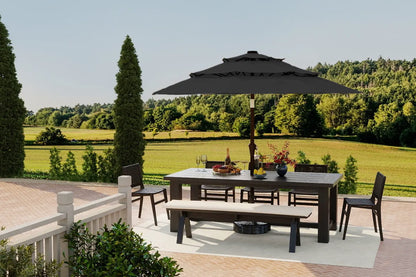 Outdoor patio set with table, chairs, and umbrella on a deck with a scenic background.