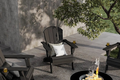 Black Adirondack chair with a pillow on a patio near a fire pit.