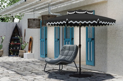 Gray chair under a black patio umbrella with decorative white trim on a stone patio.