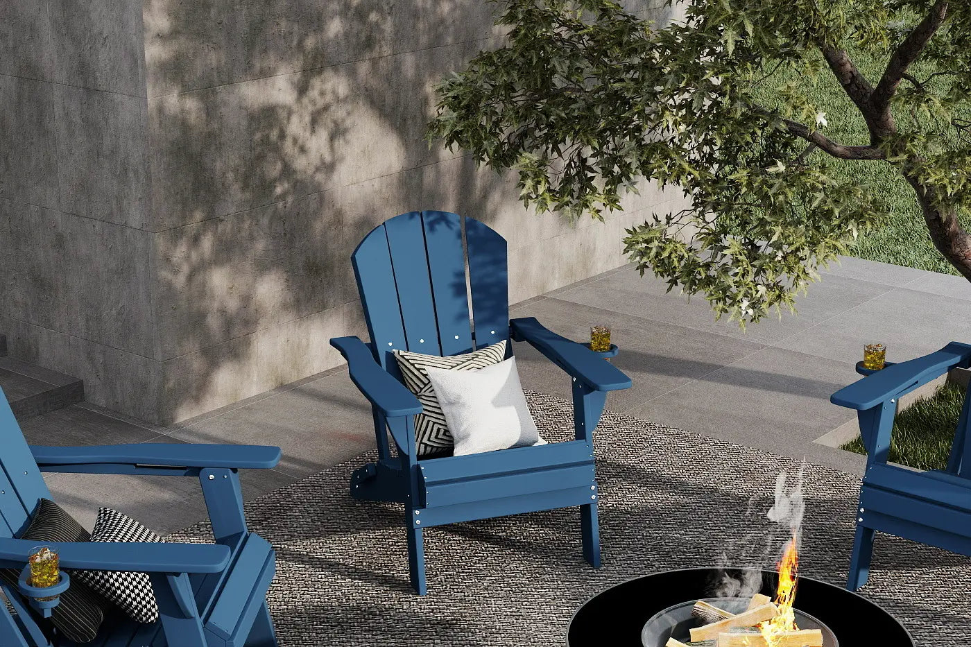 Blue Adirondack chairs around a fire pit with a tree and concrete wall in the background.