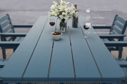 Blue outdoor table with a vase of flowers, glass of wine, and bowl of snacks on a patio setting.