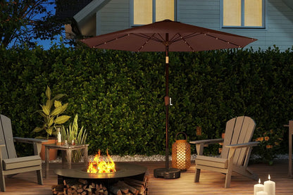 Outdoor patio setup with fire pit, chairs, and umbrella in a garden setting.