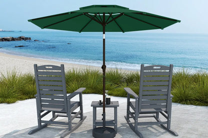 Outdoor patio set with two chairs and a table under a green umbrella by the beach.