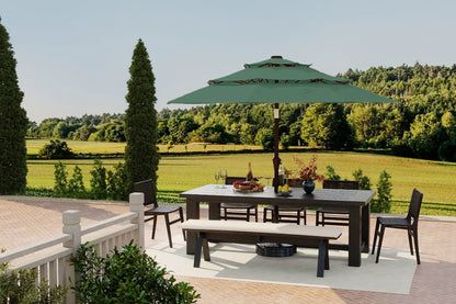 Outdoor patio set with table, chairs, and umbrella on a deck with a scenic background.