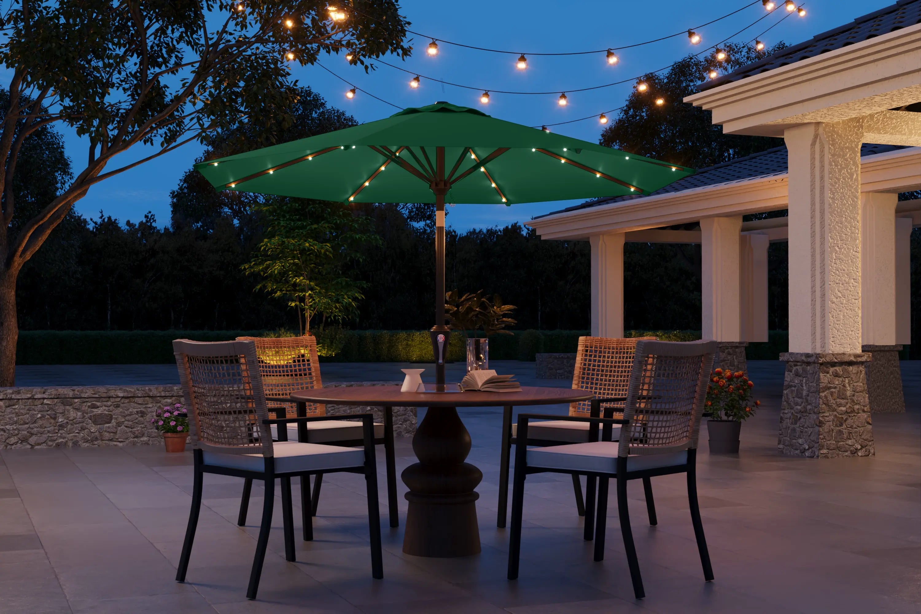 Outdoor patio set with table, chairs, and umbrella under string lights at night.