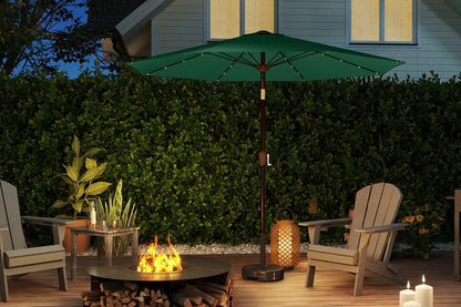 Outdoor patio setup with a fire pit, chairs, and a green umbrella under a house.