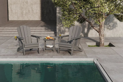 Two gray Adirondack chairs by a pool with a small table between them.