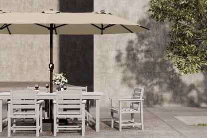 Outdoor dining set with table, chairs, and umbrella against a concrete wall.