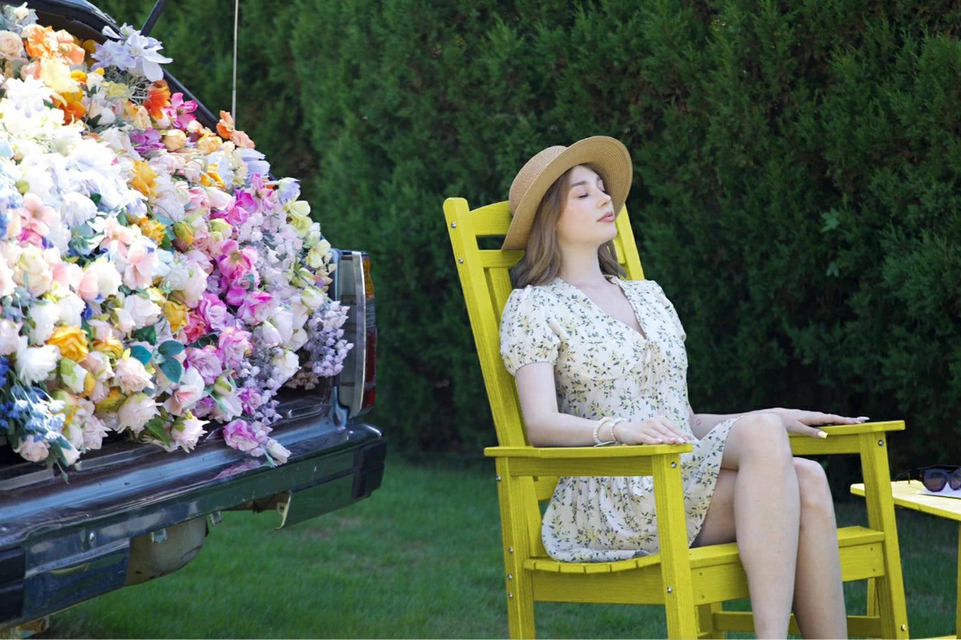 Woman sitting on a yellow chair with a truck full of flowers in the background