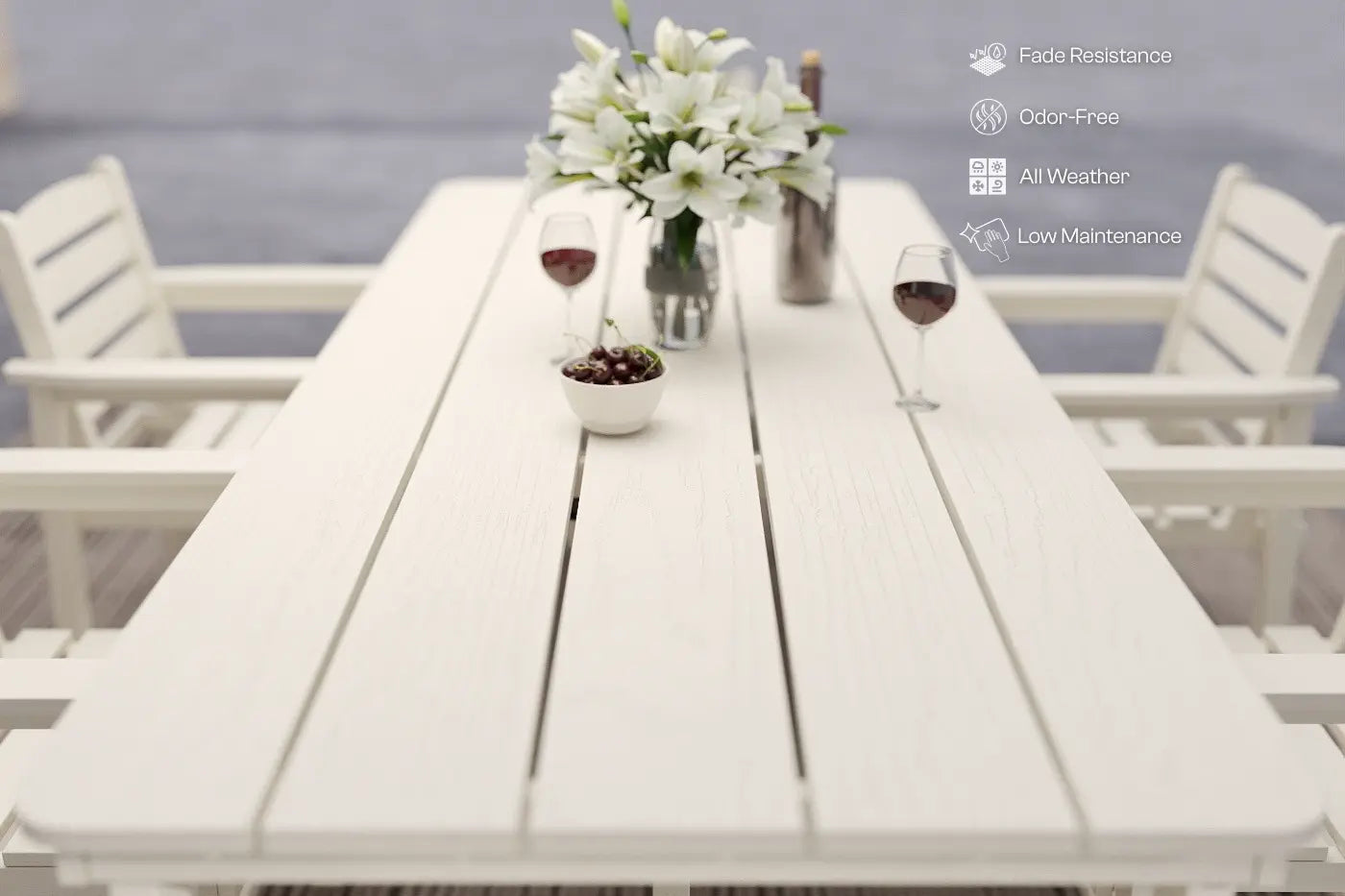 White outdoor table with flowers and glasses, surrounded by chairs, on a blurred background.