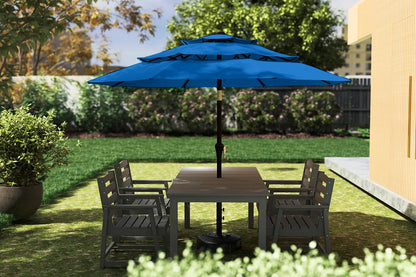 Outdoor patio set with table and chairs under a blue umbrella on a grassy area.